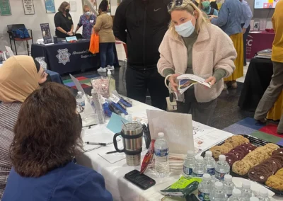 people visiting a booth with cookies and papers on the table